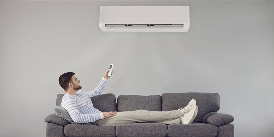 Man lying on the couch turning on ductless ac